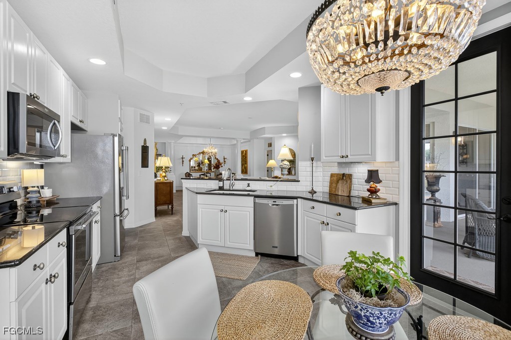 3610 Lansing Loop, Unit 102 Estero, FL 33928 - Photo 11 of 27 a kitchen with stainless steel appliances kitchen island granite countertop a refrigerator a stove a sink dishwasher and white cabinets with wooden floor