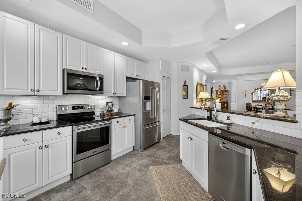3610 Lansing Loop, Unit 102 Estero, FL 33928 - Photo 12 of 27 a kitchen with stainless steel appliances granite countertop a sink stove microwave and refrigerator