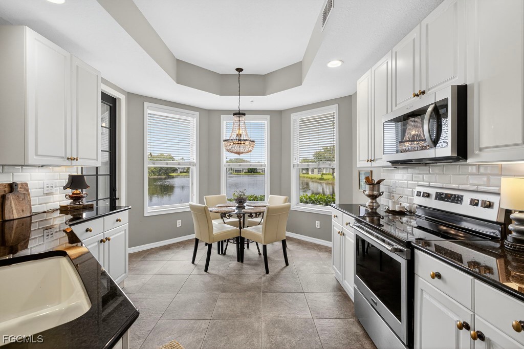 3610 Lansing Loop, Unit 102 Estero, FL 33928 - Photo 10 of 27 a kitchen with stainless steel appliances granite countertop a stove top oven a sink a dining table and chairs