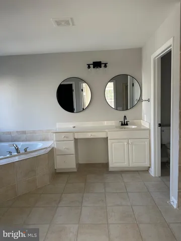 a bathroom with a double vanity sink mirror and bathtub