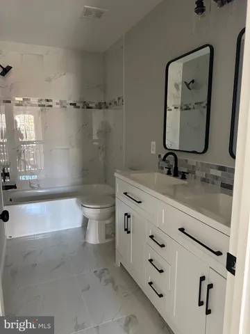 a bathroom with a granite countertop sink a toilet and bathtub