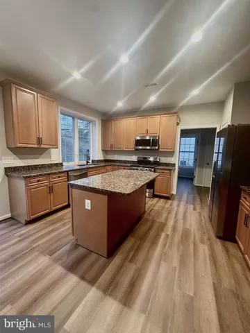 a large kitchen with stainless steel appliances granite countertop wooden cabinets a refrigerator a sink a stove a washer dryer and a refrigerator