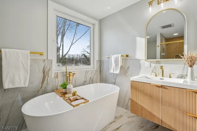 a bathroom with a tub a sink and a window