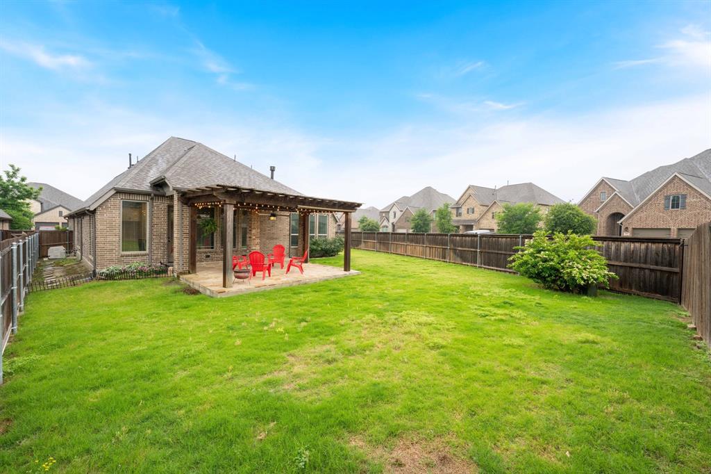 1501 Calcot Lane Forney, TX 75126 - Photo 28 of 34 Expansive backyard featuring a large green lawn, a wooden privacy fence, and a brick exterior with a rear patio