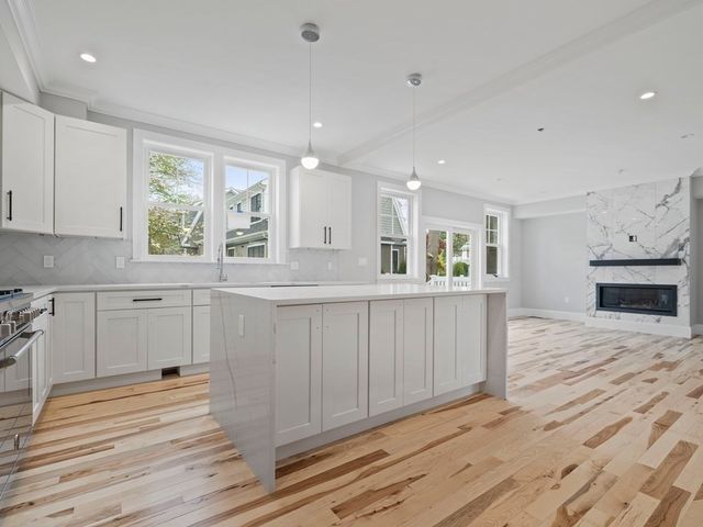 a kitchen with white cabinets and wooden floor