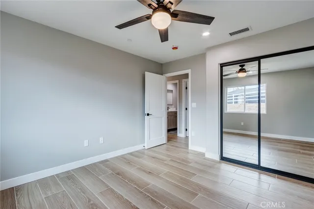 an empty room with wooden floor fan and windows