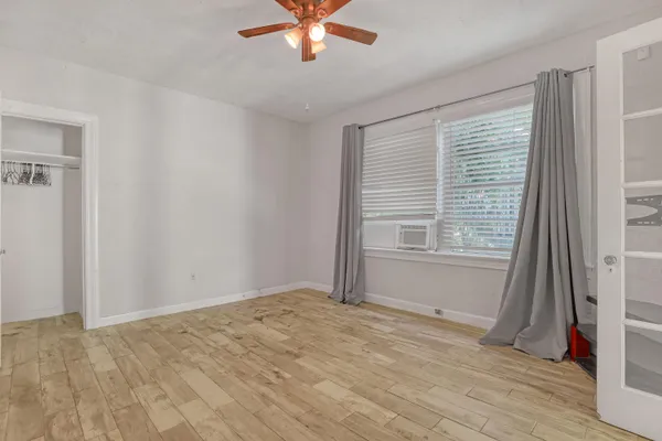 a view of empty room with wooden floor and fan