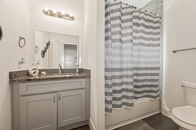 a bathroom with a granite countertop sink a toilet and a mirror