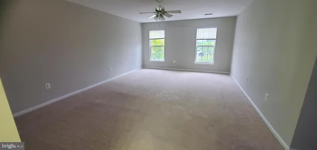 an empty room with windows and ceiling fan