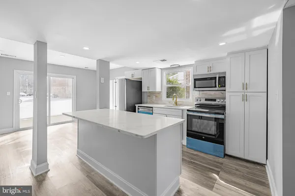 a kitchen with kitchen island a sink appliances and cabinets