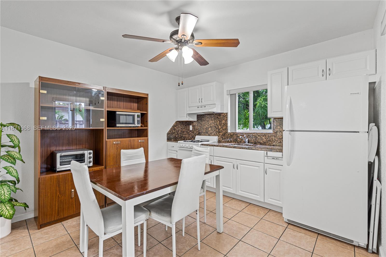 11740 Southwest 182nd Terrace Miami, FL 33177 - Photo 29 of 44 a kitchen with stainless steel appliances granite countertop a dining table chairs and a refrigerator