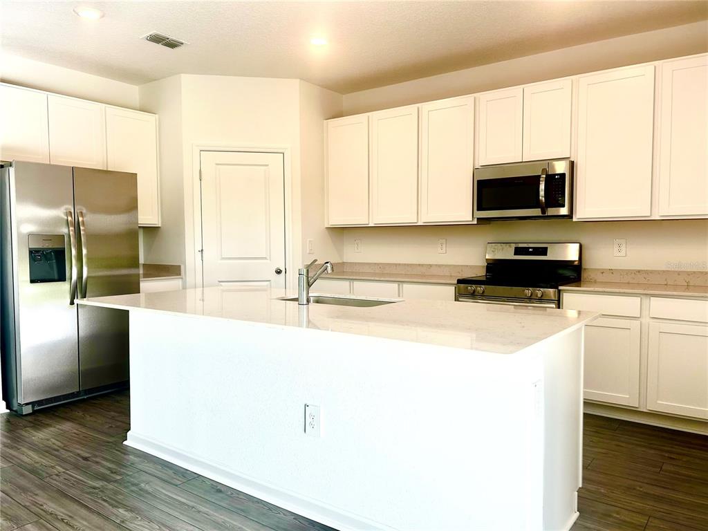 1103 Northwest 44th Court Road Ocala, FL 34482 - Photo 12 of 36 a kitchen with stainless steel appliances a sink a stove a microwave and cabinets