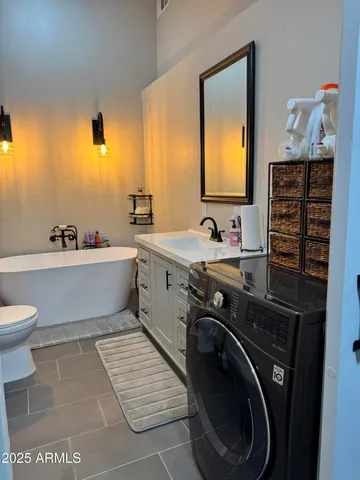 a bathroom with a bathtub sink vanity mirror and toilet