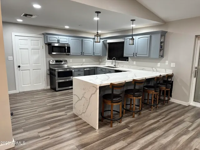 a kitchen with stainless steel appliances kitchen island granite countertop a stove a sink and a refrigerator