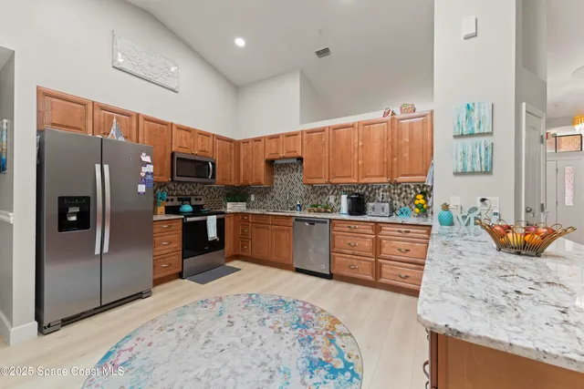 a kitchen with stainless steel appliances granite countertop a refrigerator a stove and a sink