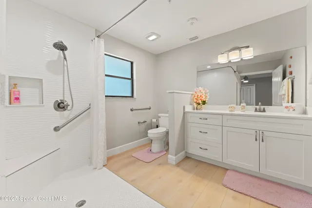 a spacious bathroom with a double vanity sink a mirror and a toilet