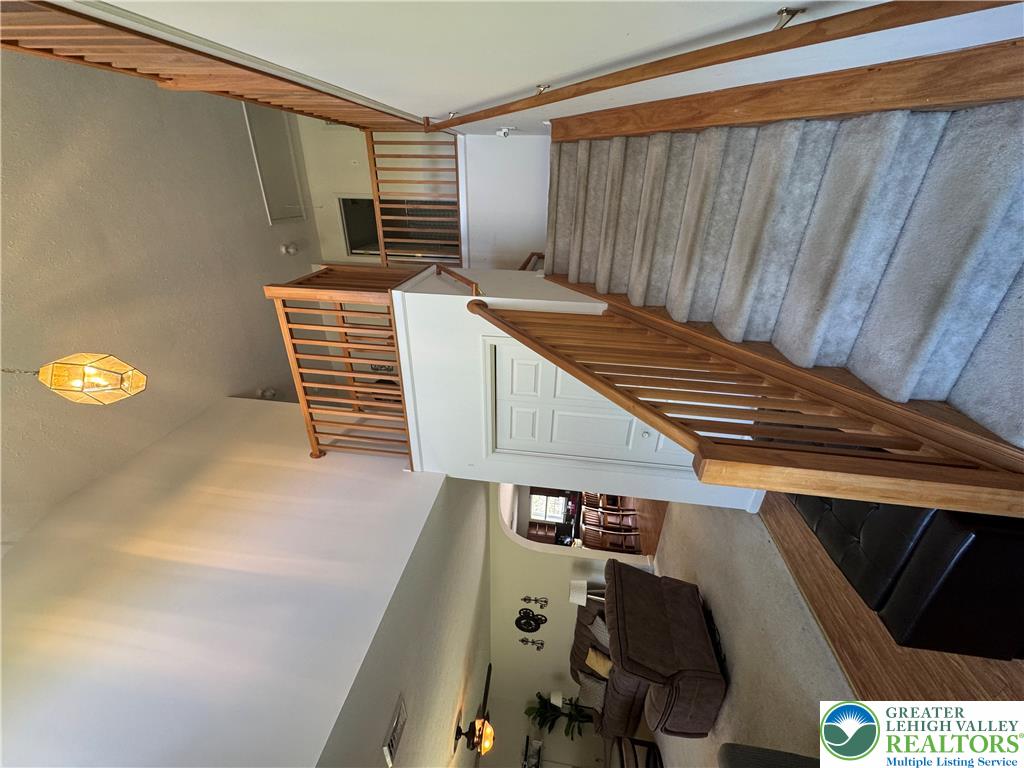 2742 Long Pond Road Long Pond, PA 18334 - Photo 18 of 57 A grand staircase with wood railings leads to an upper-level balcony, overlooking a spacious living area.