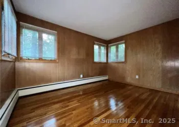 a view of an empty room with a window and wooden floor