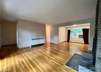 a view of an empty room with a window and wooden floor