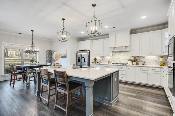 a kitchen with stainless steel appliances granite countertop a dining table chairs stove and white cabinets