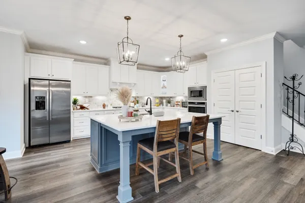 a kitchen with stainless steel appliances kitchen island granite countertop a refrigerator a stove a microwave oven a dining table and chairs with wooden floor