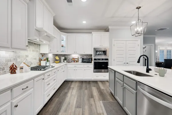 a large kitchen with stainless steel appliances granite countertop a lot of counter space and wooden floors
