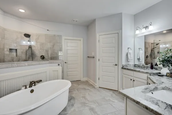 a bathroom with a tub sink double vanity and mirror