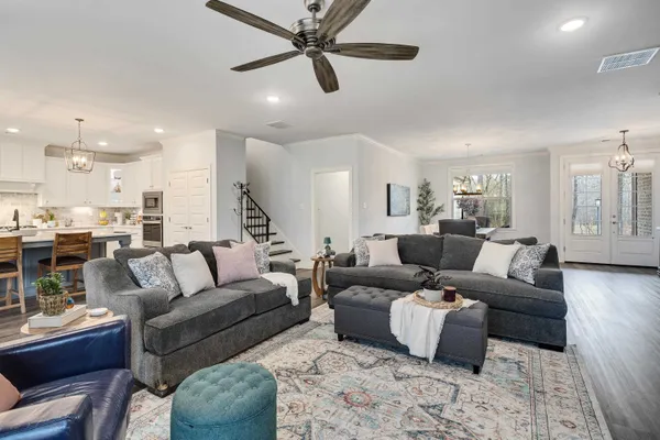 a living room with furniture kitchen view and a wooden floor