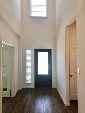 an empty room with wooden floor closet and windows