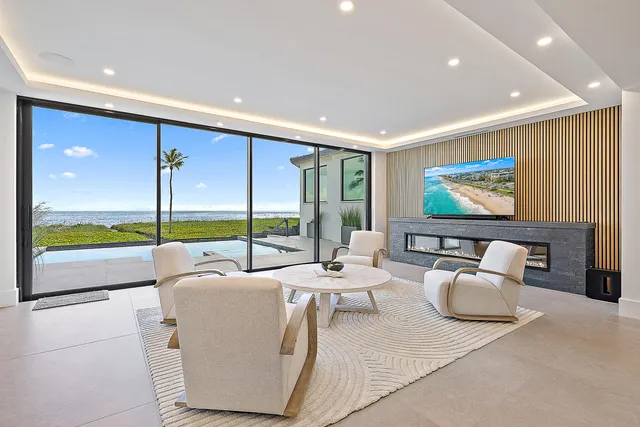 a living room with furniture floor to ceiling window hardwood floor and a flat screen tv