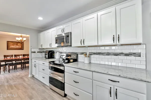 a kitchen with granite countertop white cabinets white stainless steel appliances and sink