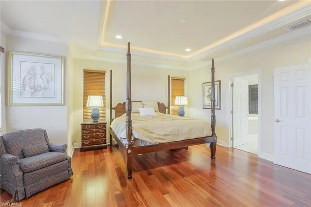 a spacious bedroom with a bed a couch and wooden floor