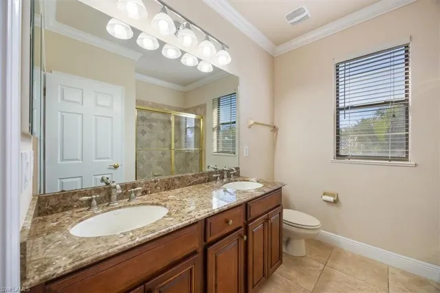 a bathroom with a granite countertop double vanity sink mirror and toilet
