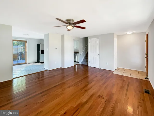 a view of empty room with wooden floor and ceiling fan