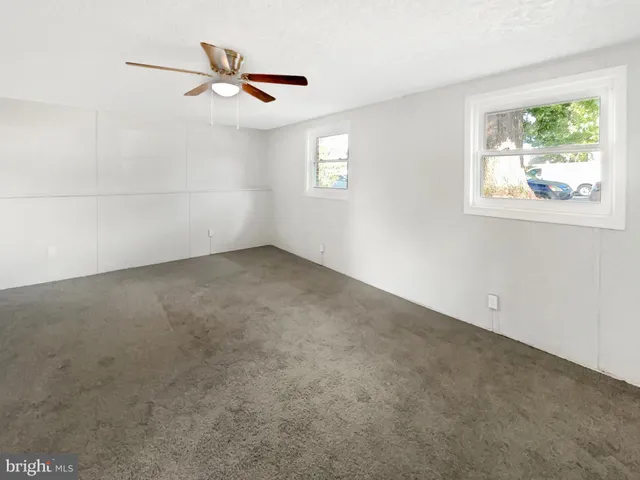 an empty room with windows and ceiling fan