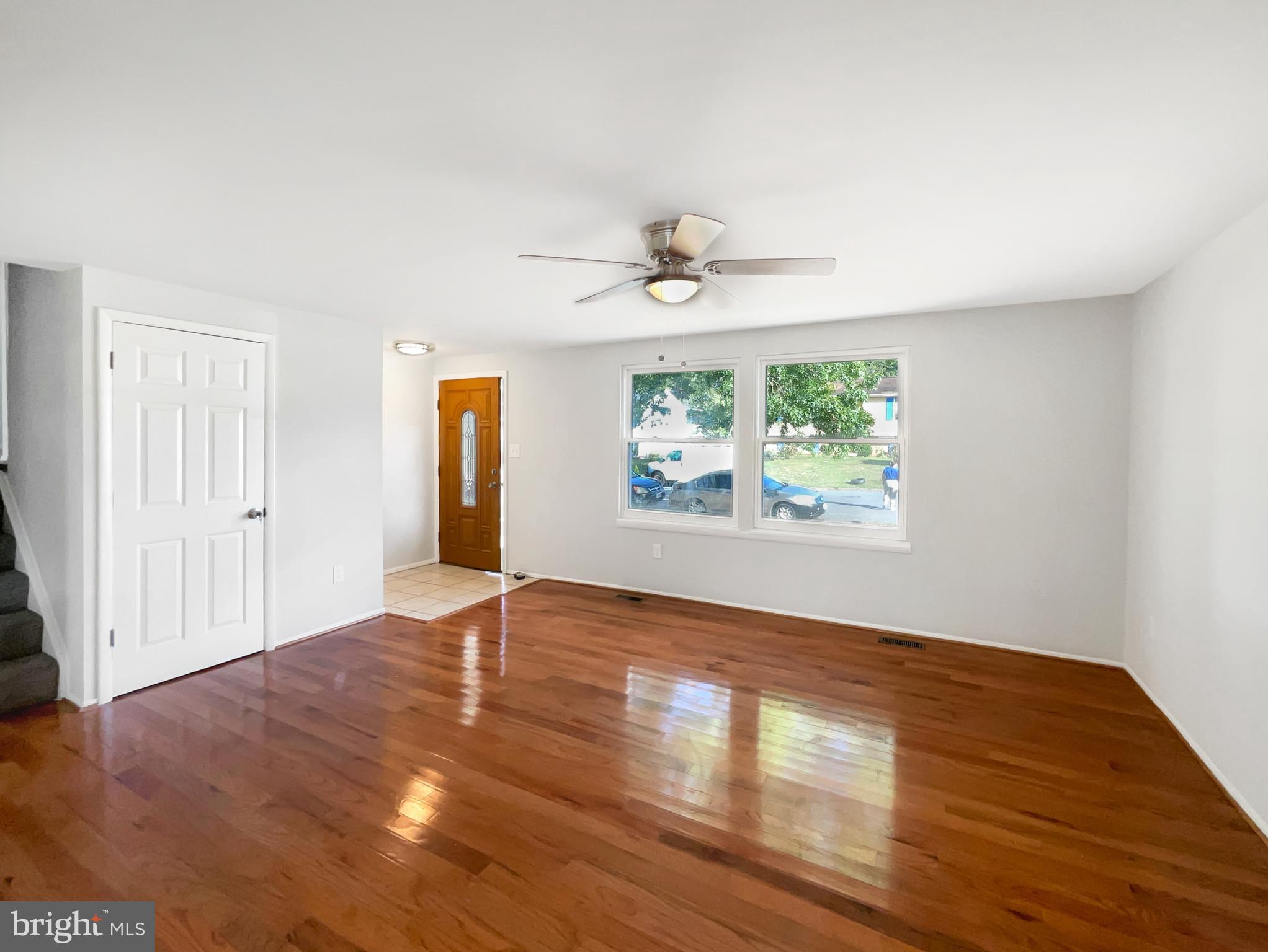 113 North Harrison Road Sterling, VA 20164 - Photo 3 of 19 an empty room with wooden floor chandelier fan and windows
