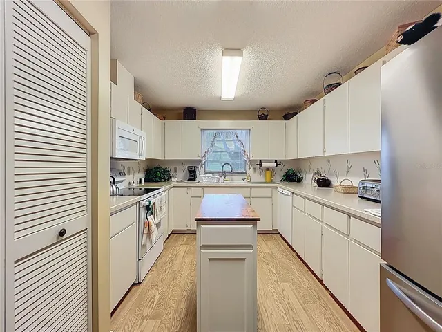 a kitchen with granite countertop white cabinets and white appliances