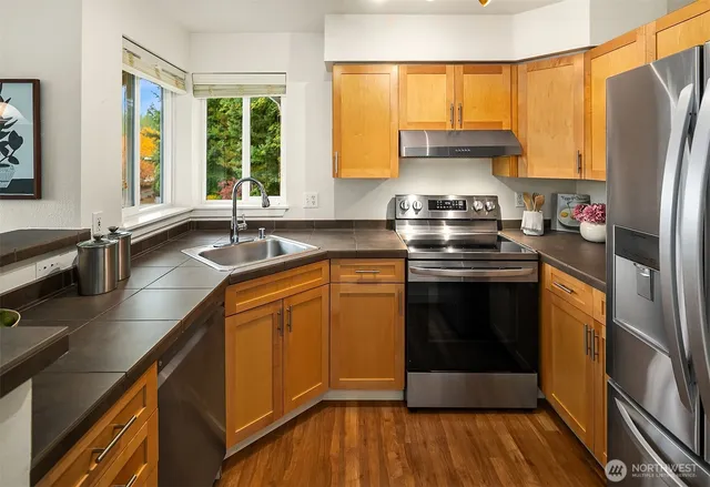 a kitchen with stainless steel appliances granite countertop a stove a sink and a refrigerator