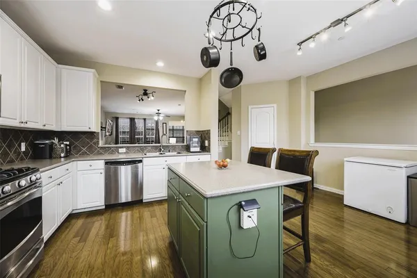 a kitchen with a sink a stove cabinets and wooden floor