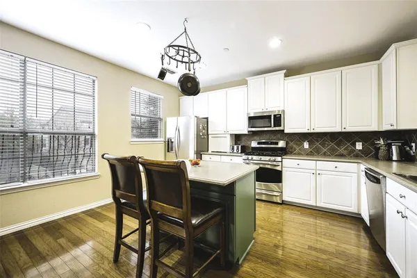 a kitchen with a stove a sink dishwasher a dining table and chairs with wooden floor