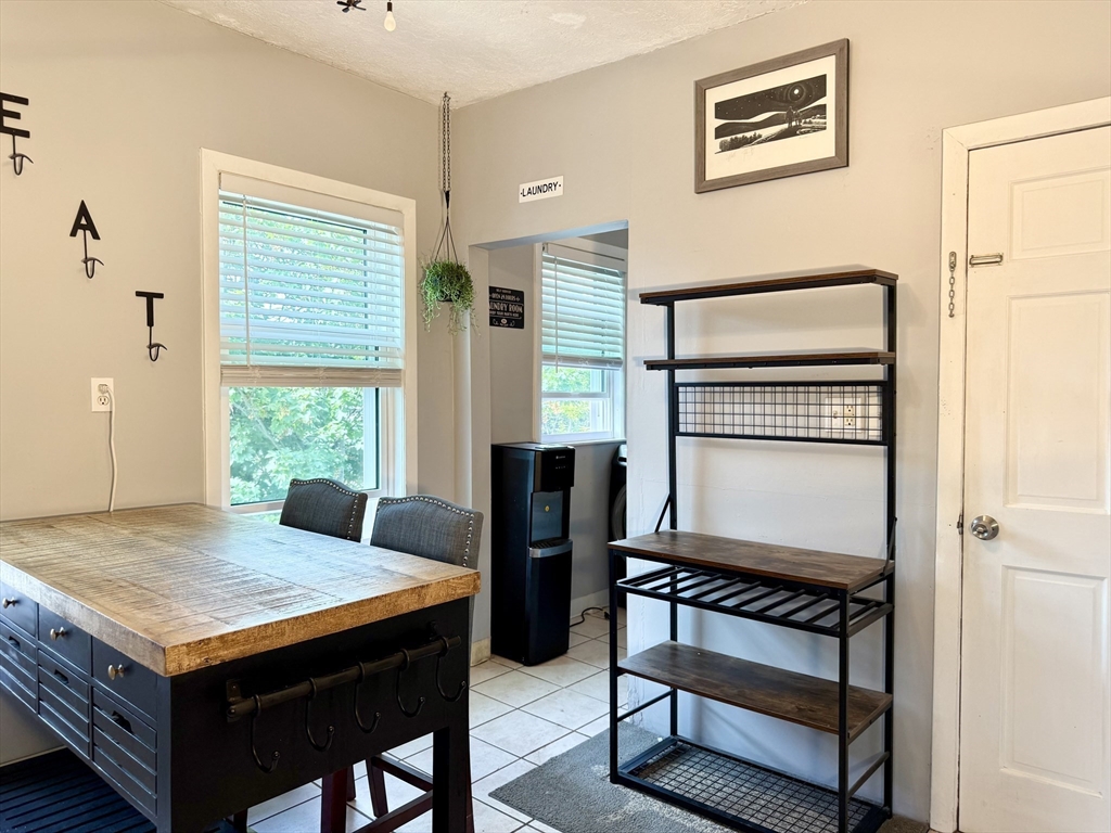 26 Forrest Street, Unit 3 Winthrop, MA 02152 - Photo 5 of 21 a living room with a table chairs and a refrigerator