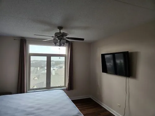 a view of a hallway to a bedroom with wooden floor and a ceiling fan