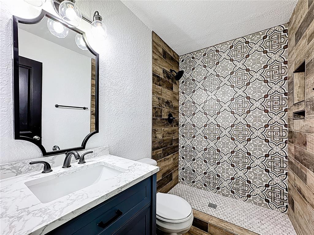 1890 Tyner Road Haines City, FL 33844 - Photo 33 of 48 a bathroom with a granite countertop toilet sink mirror and shower