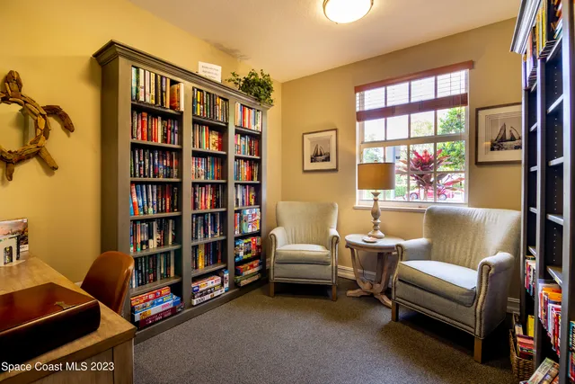 a living room with furniture a bookshelf and a window