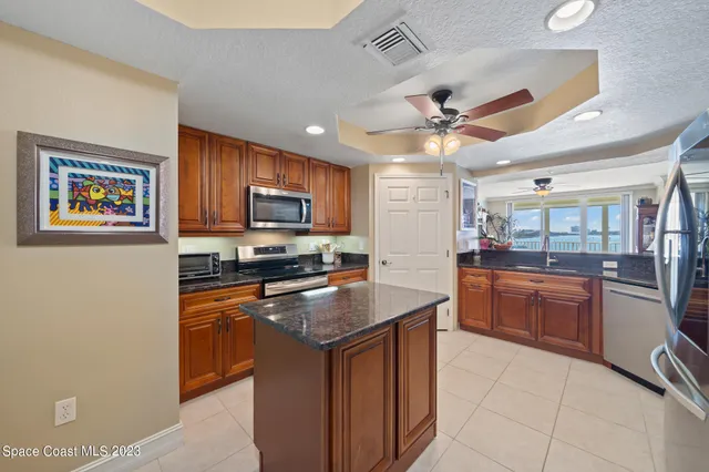 a kitchen with stainless steel appliances granite countertop a stove top oven a sink dishwasher a dining table and chairs with wooden floor