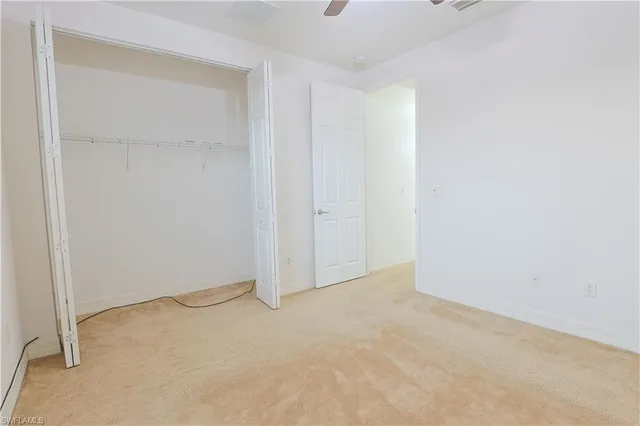 an empty room with a chandelier fan and windows