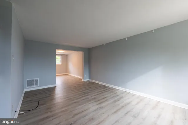 a view of an empty room with window and wooden floor