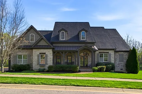 a front view of a house with a garden and trees