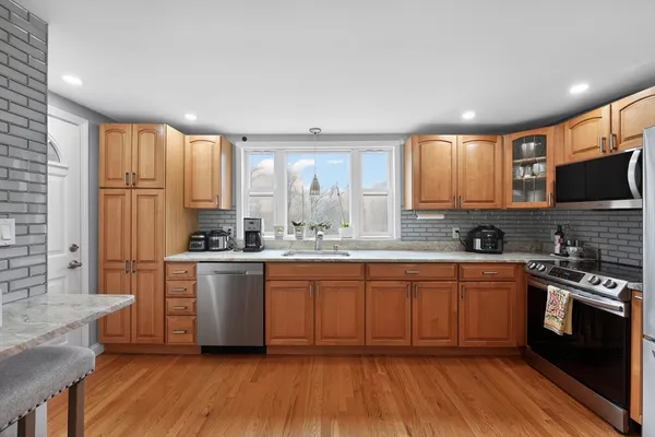 a large kitchen with stainless steel appliances granite countertop a stove a sink dishwasher and a microwave oven with wooden floor
