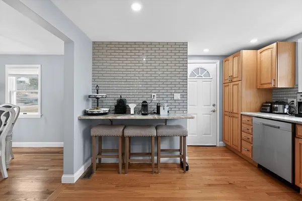 a kitchen with stainless steel appliances kitchen island granite countertop a table chairs sink and cabinets